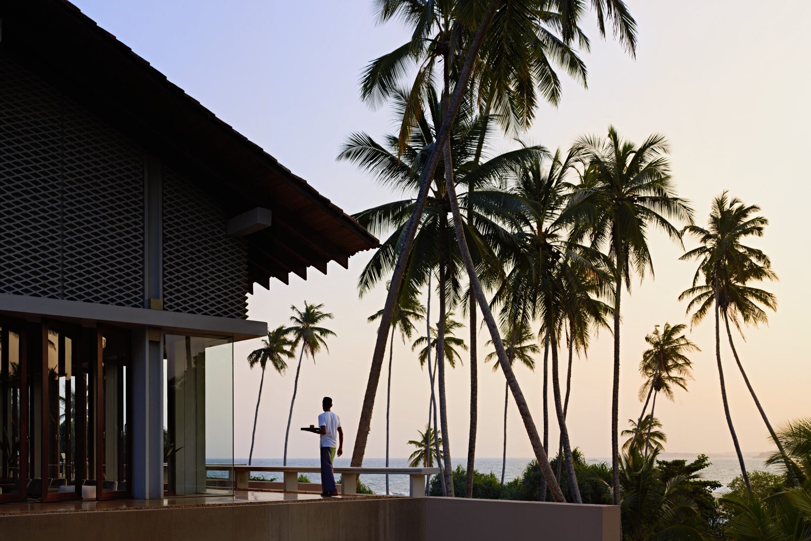 Luxury Beachfront Villa at Sunset – Sri Lanka Modern beachfront villa with palm trees overlooking the ocean at sunset in Sri Lanka