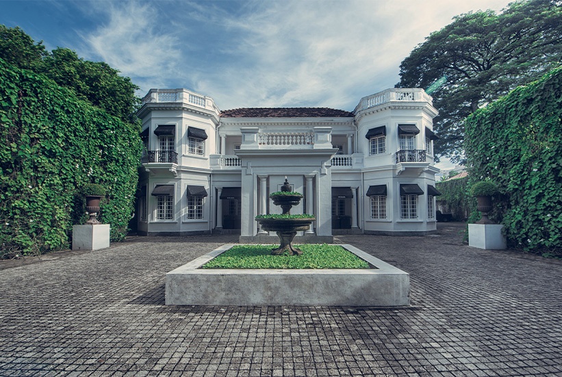 Elegant colonial-style villa with symmetrical architecture, central fountain, and lush greenery in Sri Lanka