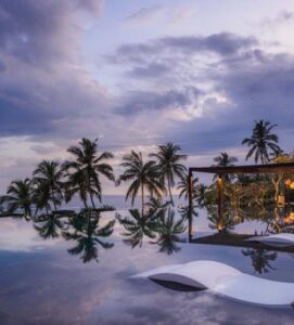 Luxury beachfront infinity pool at sunset with palm trees and ocean views in Sri Lanka